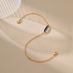 Dettaglio catena placcata oro 18K con gemma blu ovale e chiusura a moschettone regolabile