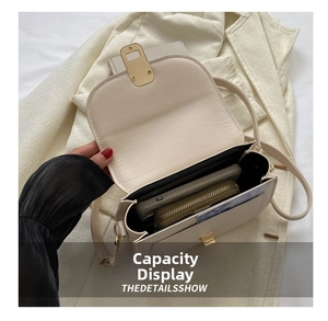Detail view of the spacious inner compartment and golden turn-lock of the beige saddle bag