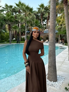Brown off-shoulder long dress with headscarf and bracelets in a luxury poolside setting