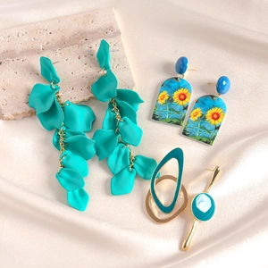 Detailed view of turquoise petal earrings and gold bangle on elegant silk fabric