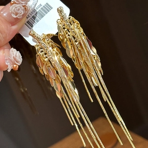Dettaglio di orecchini a nappa a spiga di grano dorata con foglie a strati e frange lunghe