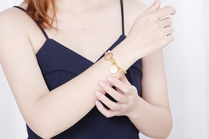 Vue rapprochée d'un bracelet doré à maillons avec pendentif disque et fermoir rond