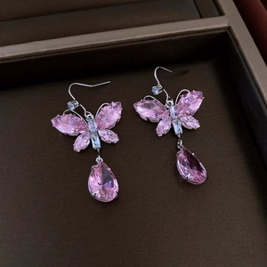 Nahaufnahme von Schmetterlingsohrringen mit rosa Kristallanhängern in Silberoptik