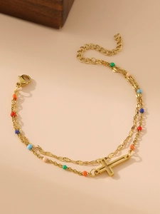 Macro detail of a 18K gold-plated double-layer bracelet with colorful beads and a cross