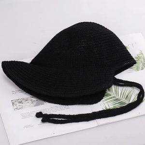 Close-up of black crochet bucket hat with adjustable tie on a minimalist magazine