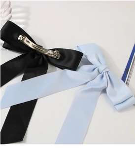 Detail view of large satin bow hair clips in black and light blue with metal spring