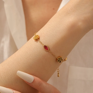 Vintage gold rose bracelet with red oval gemstone charm on a woman's wrist