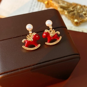 Macro view of red enamel rocking horse earrings with pearls and gold plating