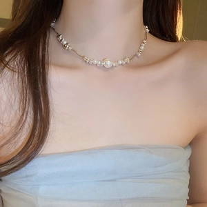Close-up of irregular silver beads and pearl necklace on model in soft warm lighting