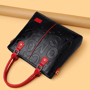 Black embossed leather tote bag with red handles and gold hardware details