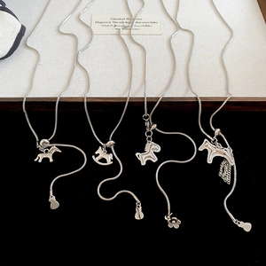 Detail view of four silver horse-themed pendants on sleek snake chains against velvet