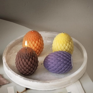 Velas detalladas de huevo de dragón con textura de escamas en cuatro colores sobre bandeja