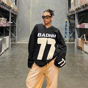 Detail of oversized black sweatshirt featuring BADNM logo and 77 print in warehouse
