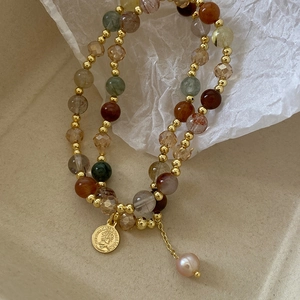 Baroque pearl bracelet with queen coin pendant and natural stones on elegant background