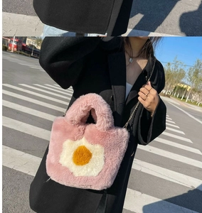 Pink plush tote bag with egg design and gold chain strap shown on a black coat