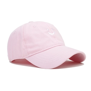Detailed close-up of pink cotton baseball cap featuring a minimalist white smiley embroidery