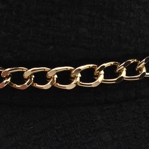 Macro detail of black tweed fabric texture with decorative gold metal chain link