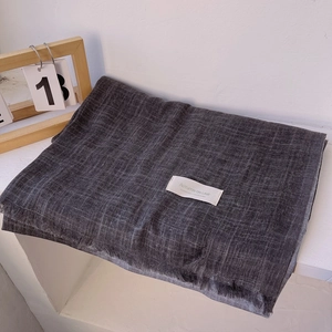 Detail of elegant dark grey linen scarf with visible texture and white woven brand label