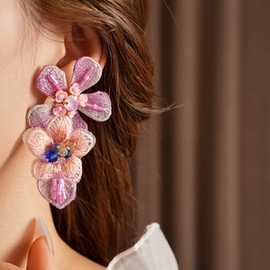 Close-up of colorful embroidered floral earring with sparkling sequins on a female model