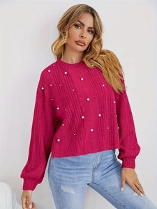 Vue détaillée du pull en tricot magenta avec texture côtelée et perles blanches élégantes