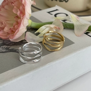 Close-up of wavy intertwined 925 sterling silver rings in gold and silver finish