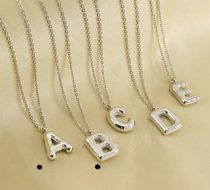 Macro shot of silver bubble letter pendants A to E made of polished stainless steel