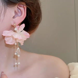 Close-up of pink fabric flower earrings with long pearl tassels and crystal pendants
