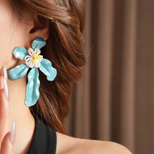 Gros plan de boucles d'oreilles fleurs bleues avec perles portées par un mannequin de profil