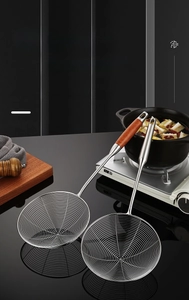 Close-up of 304 stainless steel skimmer with wood handle on dark kitchen counter