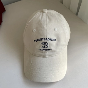Détail de la broderie lettre B bleu marine sur une casquette en coton beige