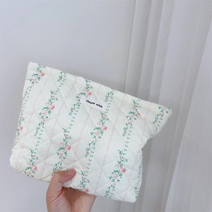 Close-up of a floral quilted makeup bag with pink flower patterns and a woven label