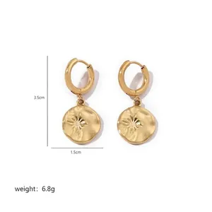 Detail view of gold matte drop earrings with hammered finish and starburst pattern