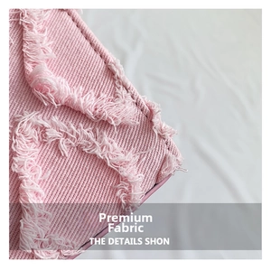 Close-up of pink twill fabric with fringed edges and textured tassel detail