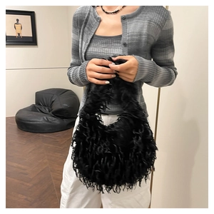 Chic black faux fur handbag with fringe detail shown on shoulder with casual outfit