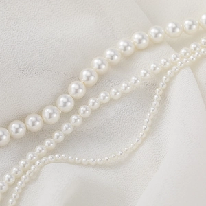 Three-layer gradient natural shell pearl necklace displayed on white chiffon fabric