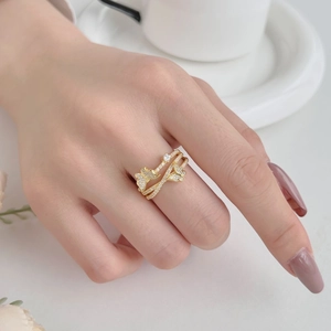 Close-up of golden butterfly ring with white zircons on hand with elegant background