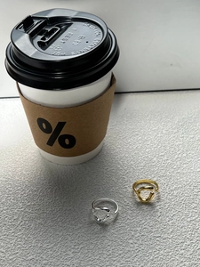 Detail of minimalist intertwined gold and silver knot rings on a textured stone surface