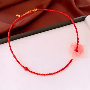 Red beaded necklace with pink flower pendant and golden adjustable chain on satin