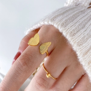Golden butterfly and bead rings in 18K gold plated titanium steel on a model hand