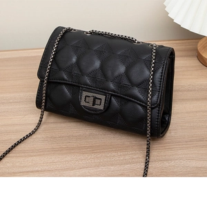 Detail of black quilted leather bag with elegant metal chain strap and twist lock closure