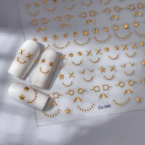 3D gold embossed nail stickers with smile faces and stars on white faux nail tips