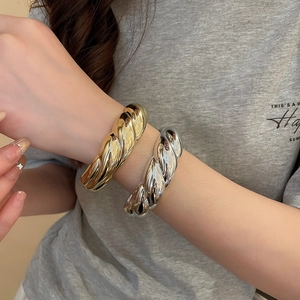 Macro detail of gold and silver twisted cuff bracelets with high polish metallic finish