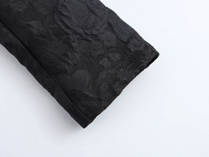 Detailed macro view of the black jacquard floral pattern on the coat cuff and fabric texture