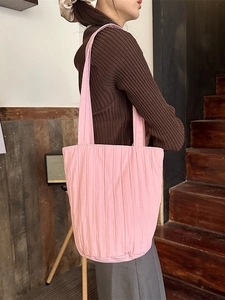 Roze geplooide stoffen bucket bag getoond op een model in een vintage interieur