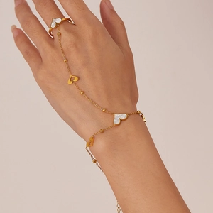 Detail of gold hand chain bracelet with heart-shaped ring and white mother of pearl inlay