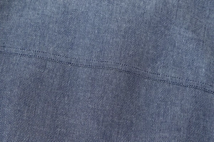 Makroaufnahme von blauem Fischgrätstoff mit präzisen Nahtdetails auf einer Anzughose