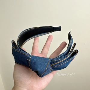Detail of blue denim headband with orange contrast stitching and fabric bow knot