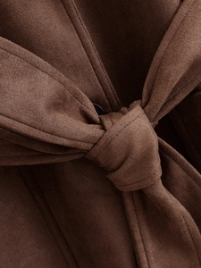 Close-up of a tied belt on a dark brown faux suede trench coat showing fabric texture