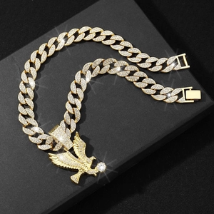 Close-up of gold iced out Cuban chain necklace with an eagle pendant on a black stand