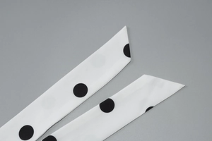 Detail shot of black and white polka dot scarf fabric showing fine texture and hemmed edges